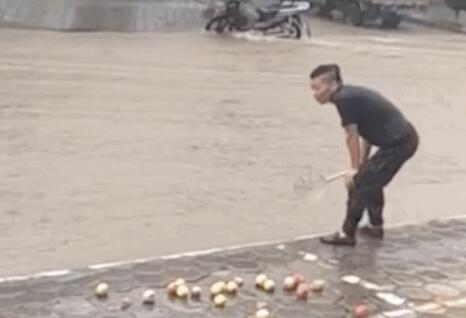 暴雨中男子用漏勺在门口捞苹果